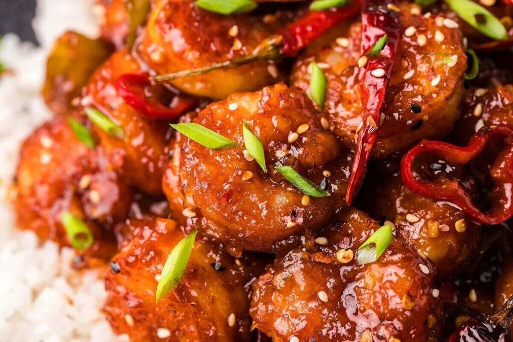 Easy General Tso Shrimp Stir Fry served over rice, garnished with green onions and sesame seeds.