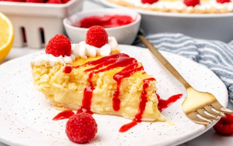 A slice of lemon pie with raspberries on top.