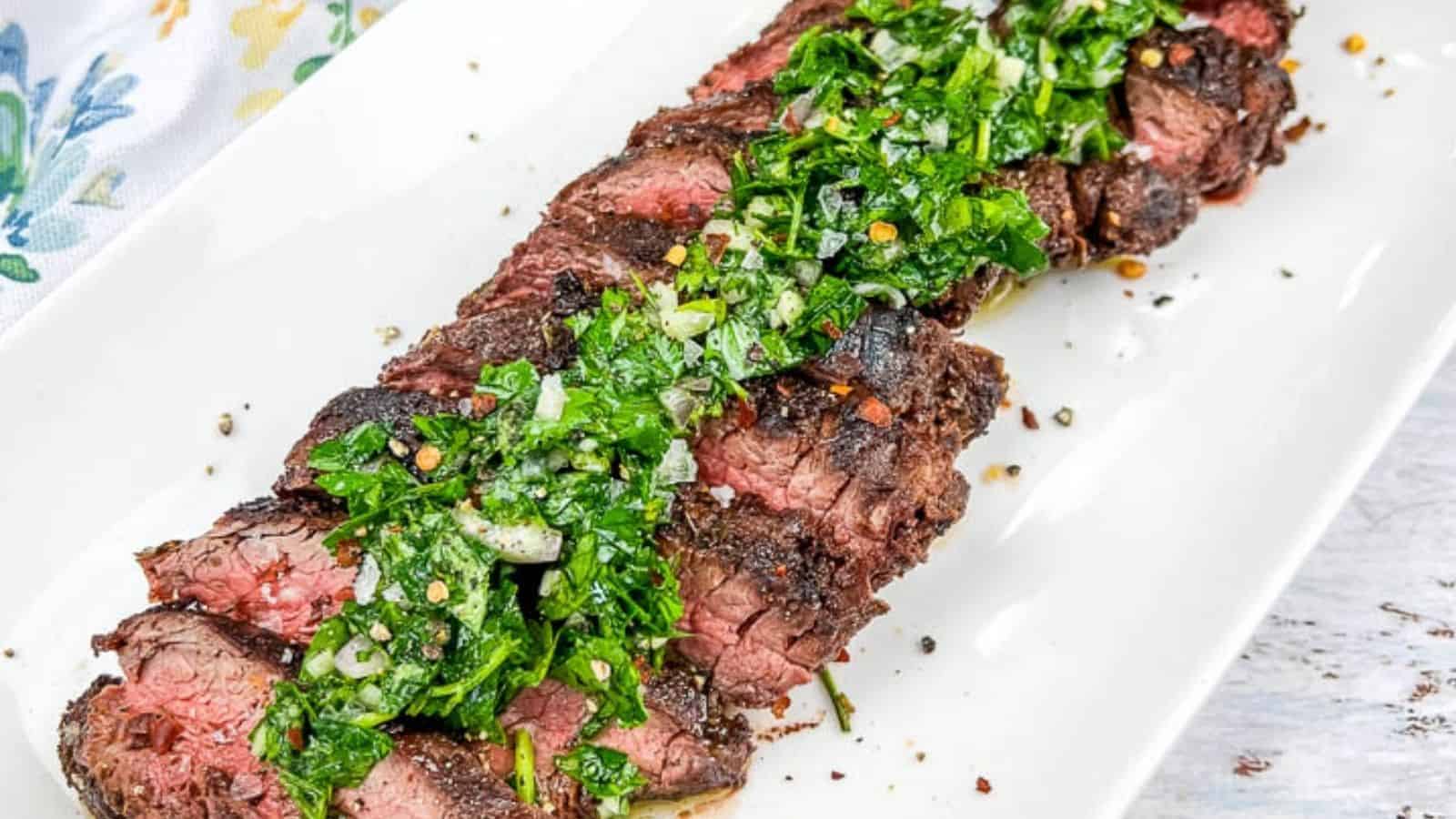 A plate of sliced Grilled Hanger Steaks with Chimichurri, served on a white rectangular dish.