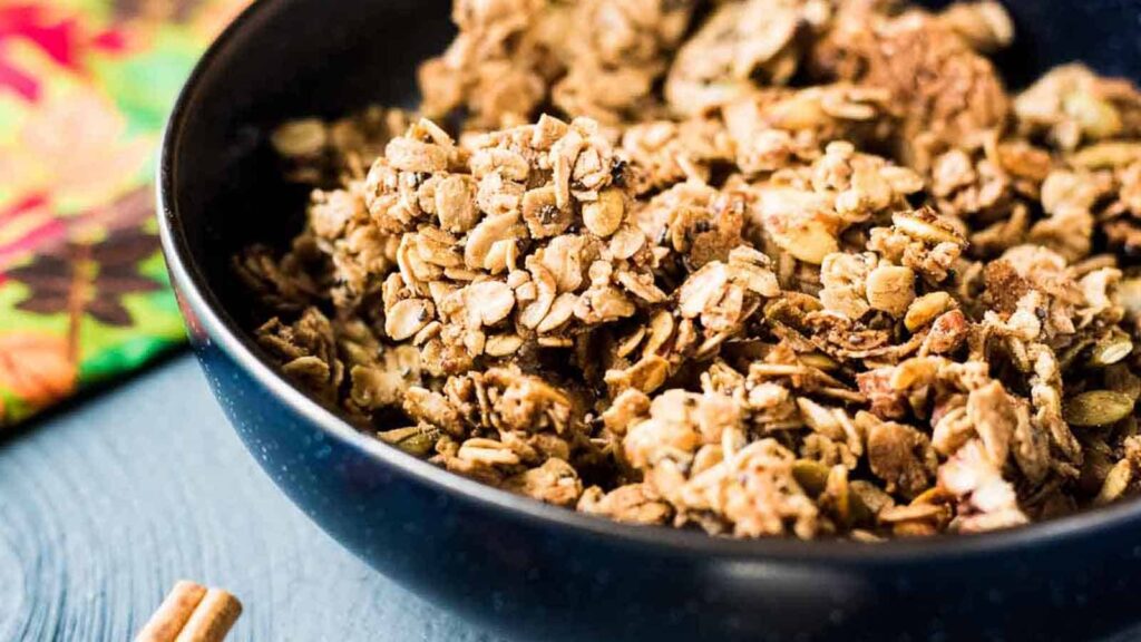 A serving of Crunchy Baked Breakfast Granola with Pumpkin Seeds in a dark bowl.