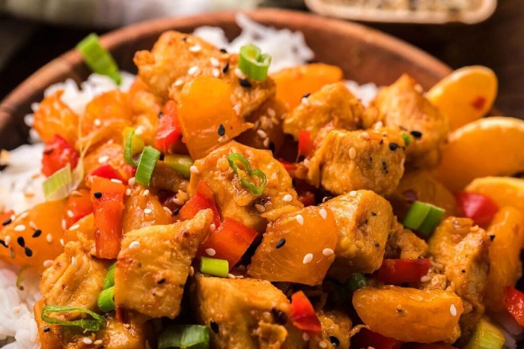 A Tangerine Chicken Stir Fry dish with vegetables and sesame seeds served over rice.